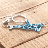 Del-Sol-Color-changing-Metal-Whale-Keychain-Blue on a wooden table top.